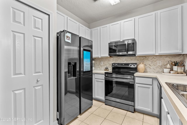 kitchen featuring white cabinetry, light tile patterned floors, tasteful backsplash, and stainless steel appliances