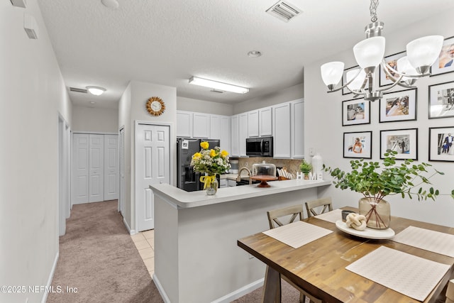 kitchen featuring white cabinets, refrigerator with ice dispenser, a kitchen breakfast bar, light colored carpet, and kitchen peninsula