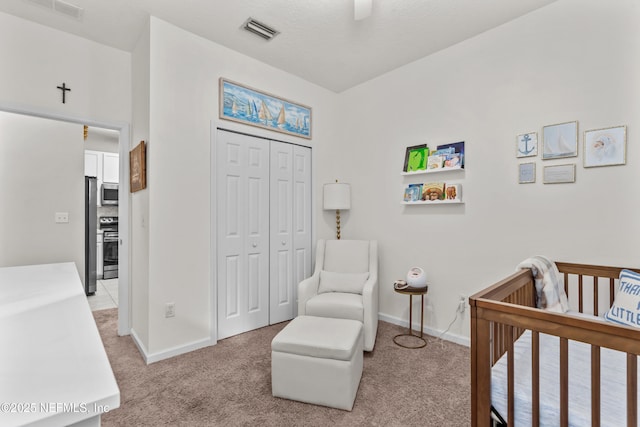 bedroom featuring a crib, a closet, ceiling fan, and carpet flooring