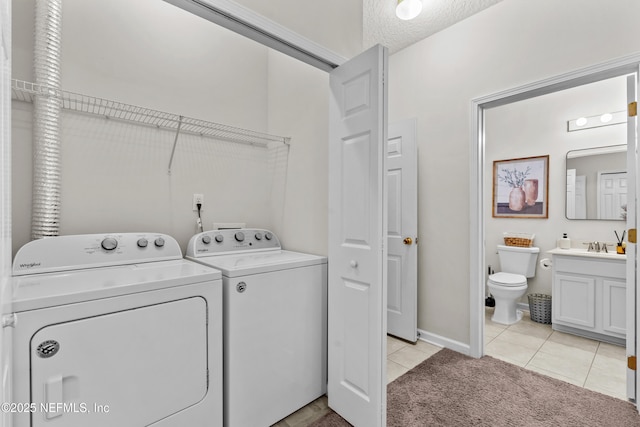 clothes washing area with separate washer and dryer, sink, light tile patterned floors, and a textured ceiling