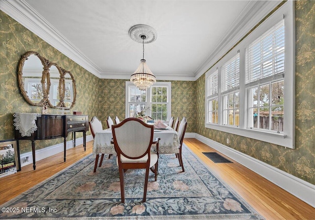 dining room with hardwood / wood-style flooring, crown molding, and a chandelier