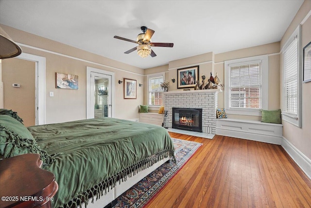 bedroom with ceiling fan, hardwood / wood-style floors, and a fireplace