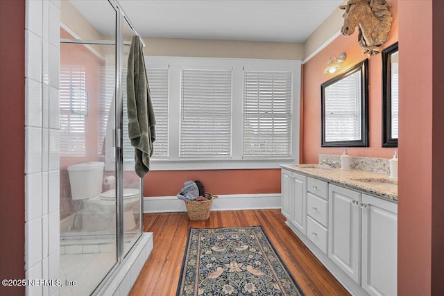 bathroom featuring hardwood / wood-style flooring, vanity, toilet, and walk in shower