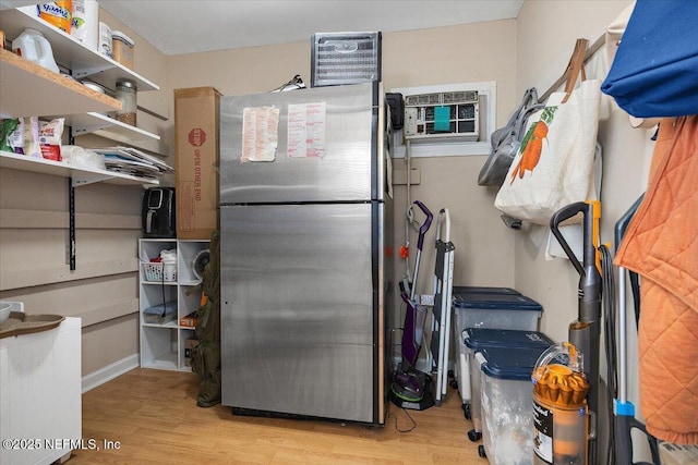 kitchen with stainless steel refrigerator, light hardwood / wood-style floors, and a wall unit AC