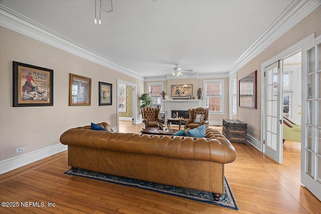 living room featuring crown molding, a fireplace, light hardwood / wood-style floors, and french doors