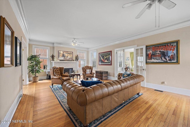 living room featuring crown molding, ceiling fan, a fireplace, and light hardwood / wood-style floors