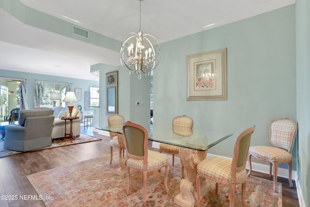 dining area with hardwood / wood-style flooring and an inviting chandelier