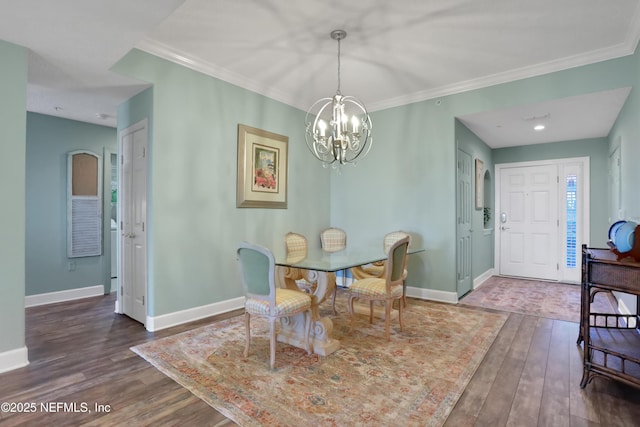 dining area with dark hardwood / wood-style flooring, crown molding, and an inviting chandelier