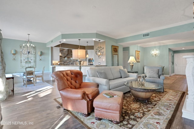 living room featuring crown molding, wood-type flooring, and a chandelier