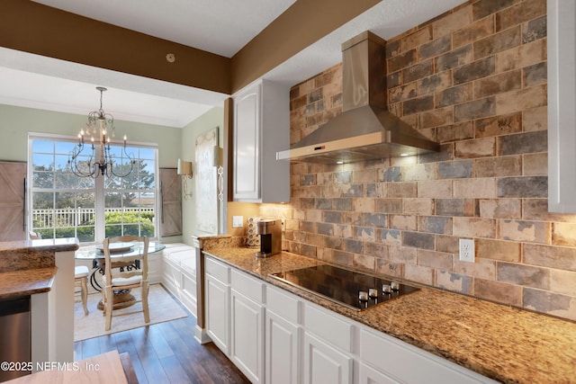 kitchen with stone counters, pendant lighting, white cabinetry, wall chimney range hood, and black electric cooktop