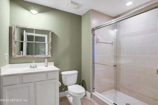 bathroom featuring toilet, vanity, and a shower with shower door