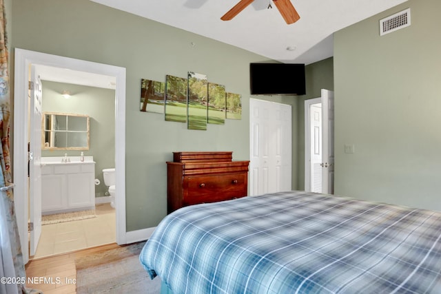 bedroom with ceiling fan, light hardwood / wood-style floors, sink, and ensuite bath