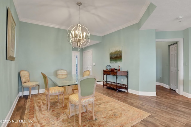 dining room with hardwood / wood-style flooring, crown molding, and a notable chandelier