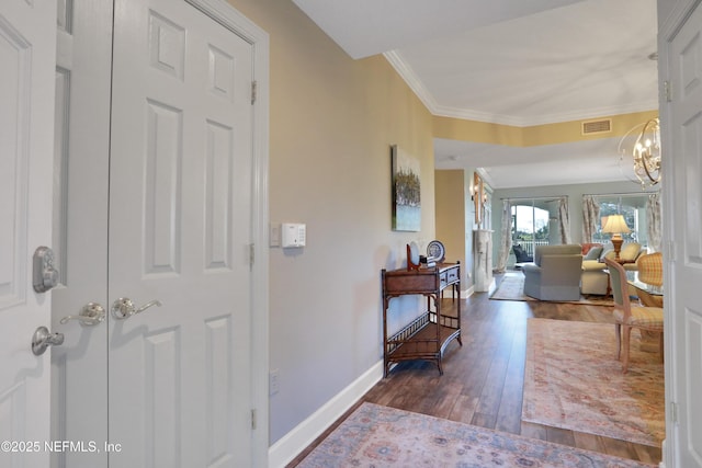 foyer entrance featuring ornamental molding, a notable chandelier, and dark hardwood / wood-style flooring