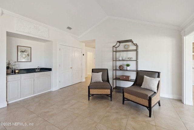 sitting room with light tile patterned floors, crown molding, vaulted ceiling, and indoor wet bar