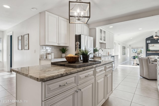 kitchen with white cabinetry, light tile patterned floors, stainless steel refrigerator, and a kitchen island