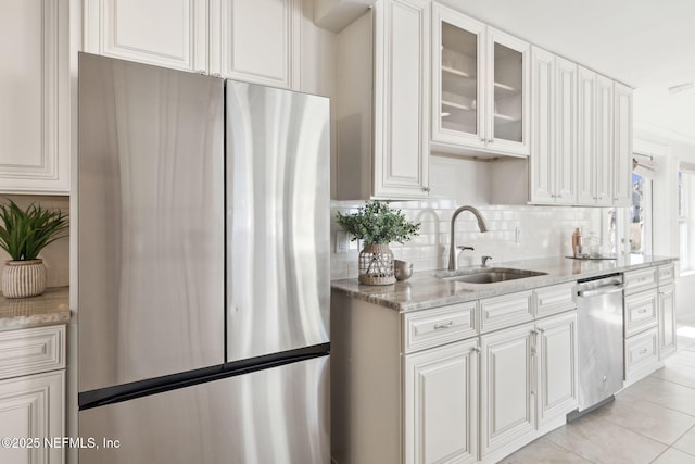 kitchen featuring sink, appliances with stainless steel finishes, light stone counters, white cabinets, and decorative backsplash