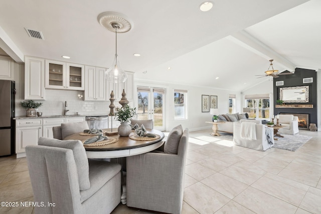 dining space featuring sink, ceiling fan, lofted ceiling with beams, light tile patterned flooring, and french doors