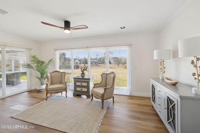 living area featuring ornamental molding, light hardwood / wood-style floors, ceiling fan, and plenty of natural light