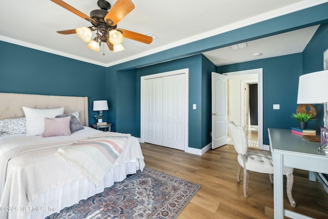 bedroom featuring ornamental molding, hardwood / wood-style floors, ceiling fan, and a closet