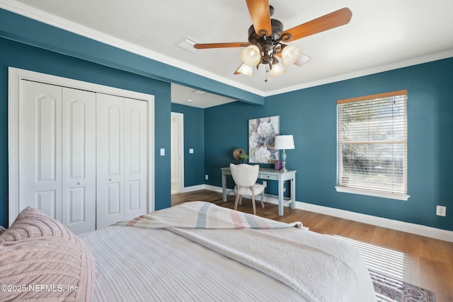 bedroom with ornamental molding, hardwood / wood-style floors, ceiling fan, and a closet