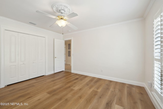 unfurnished bedroom featuring crown molding, hardwood / wood-style flooring, a closet, and ceiling fan