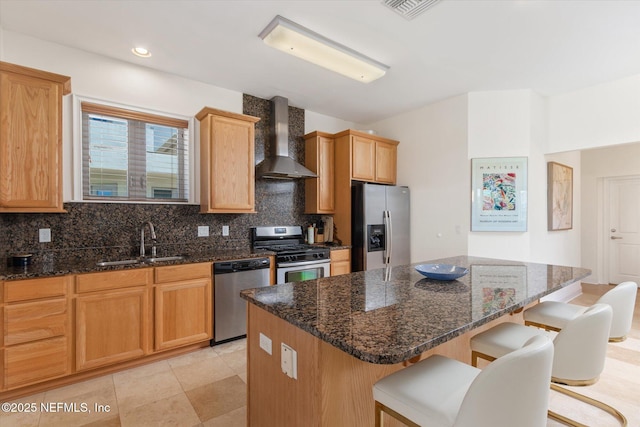 kitchen featuring a breakfast bar, sink, a center island, stainless steel appliances, and wall chimney exhaust hood