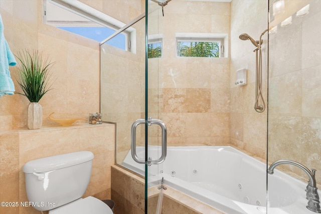 bathroom with tiled tub, a healthy amount of sunlight, tile walls, and toilet