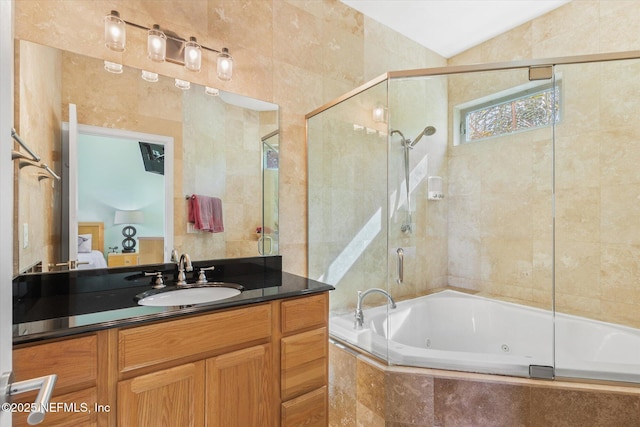 bathroom featuring vanity, independent shower and bath, vaulted ceiling, and tile walls