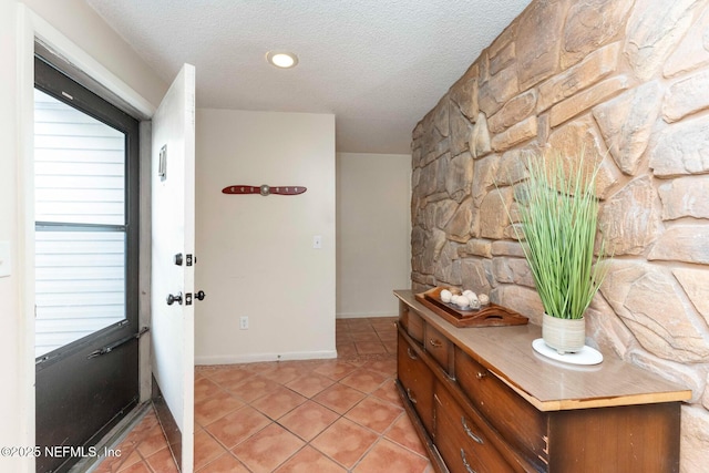 hallway featuring light tile patterned flooring, a textured ceiling, and baseboards