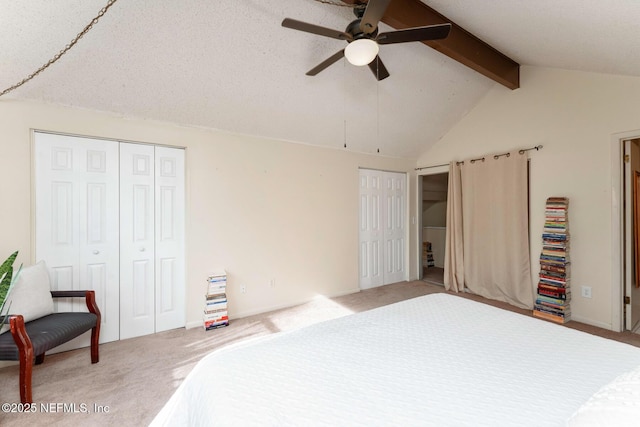 carpeted bedroom featuring ceiling fan, lofted ceiling with beams, and two closets