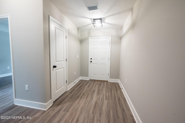 corridor with hardwood / wood-style floors and a textured ceiling