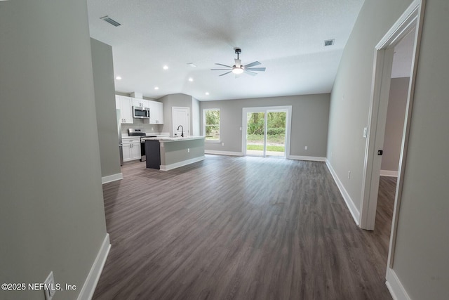 unfurnished living room featuring sink, dark wood-type flooring, ceiling fan, a textured ceiling, and vaulted ceiling