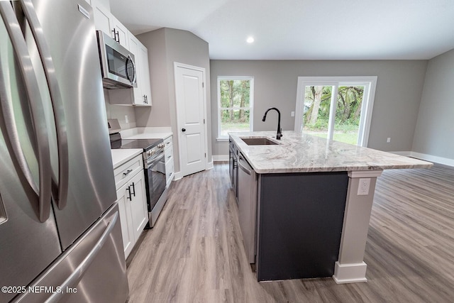 kitchen with a kitchen island with sink, light stone counters, white cabinets, and appliances with stainless steel finishes