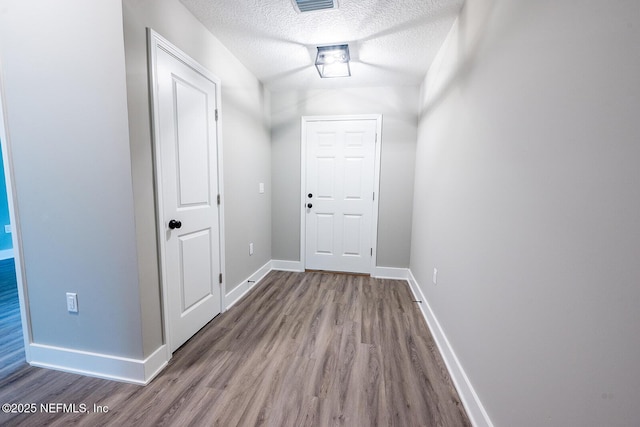 hall with hardwood / wood-style flooring and a textured ceiling