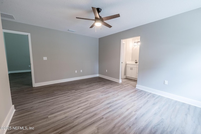 empty room with sink, a textured ceiling, ceiling fan, and light wood-type flooring