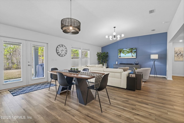 dining room featuring hardwood / wood-style flooring, vaulted ceiling, an inviting chandelier, and french doors