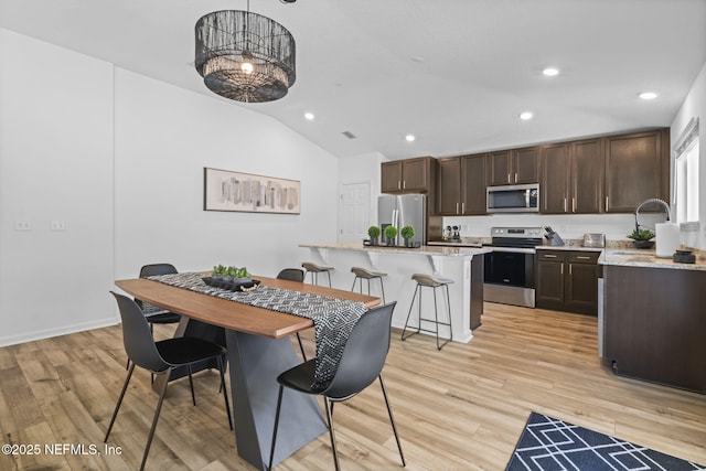 dining room featuring lofted ceiling and light hardwood / wood-style floors