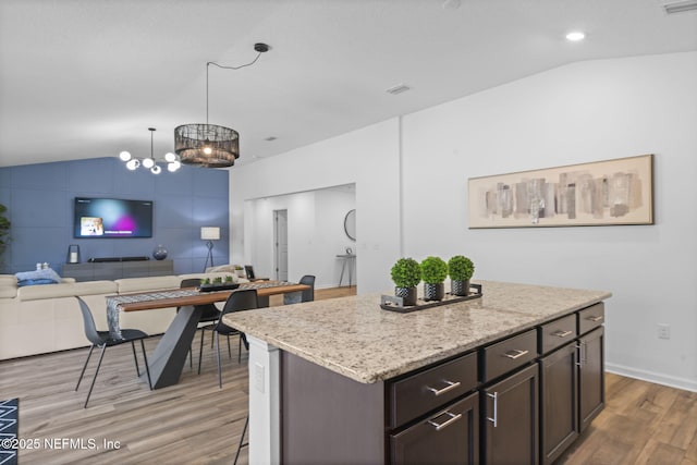 kitchen with pendant lighting, lofted ceiling, a center island, and dark brown cabinets