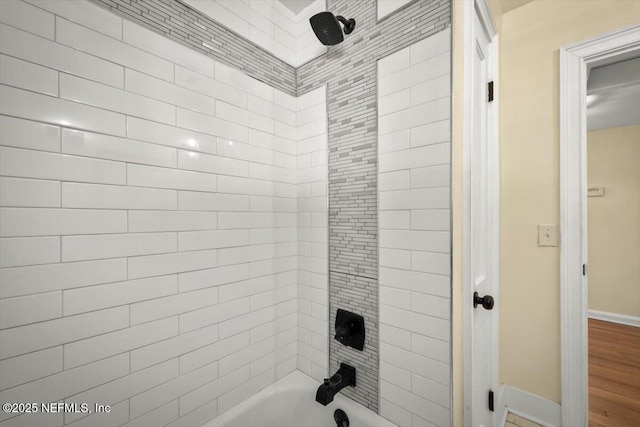 bathroom with hardwood / wood-style floors and tiled shower / bath