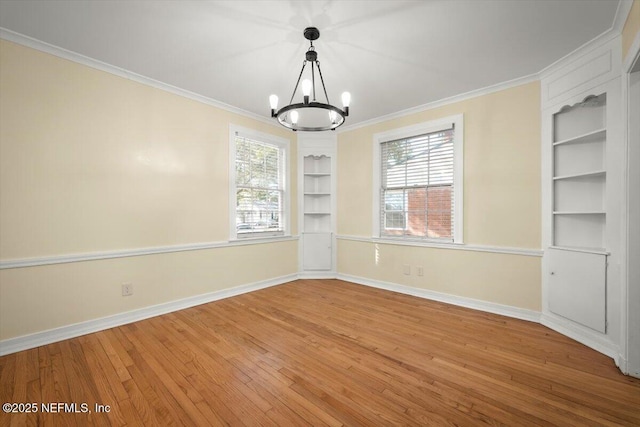 unfurnished dining area featuring an inviting chandelier, hardwood / wood-style flooring, ornamental molding, and built in shelves