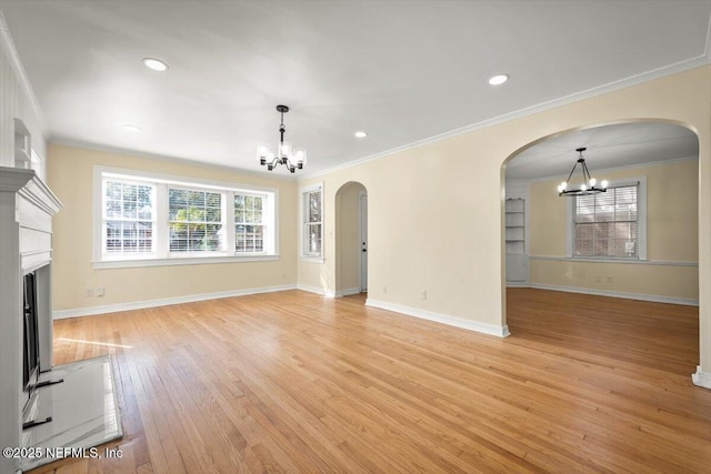 unfurnished living room featuring ornamental molding, a chandelier, and light hardwood / wood-style floors