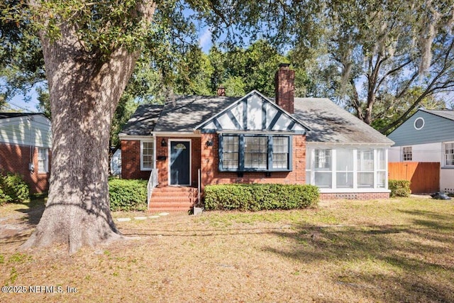 view of front of house with a front yard and a sunroom