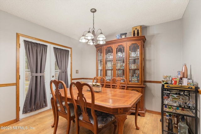 dining space featuring a chandelier, a textured ceiling, and light wood-type flooring