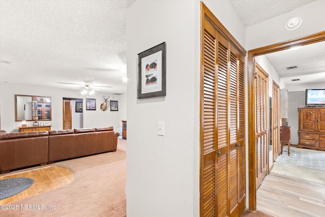 hall featuring light carpet and a textured ceiling