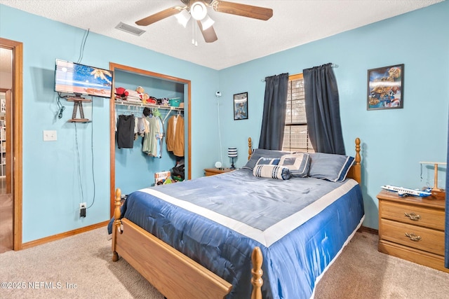 bedroom with light carpet, ceiling fan, a closet, and a textured ceiling