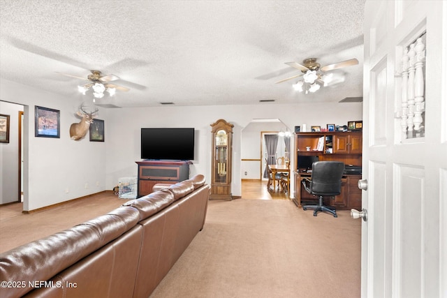 living room featuring built in desk, light colored carpet, a textured ceiling, and ceiling fan