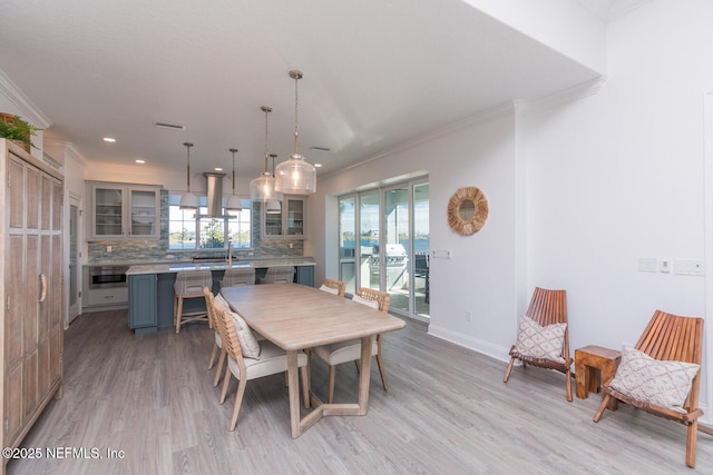 dining room with crown molding and light wood-type flooring