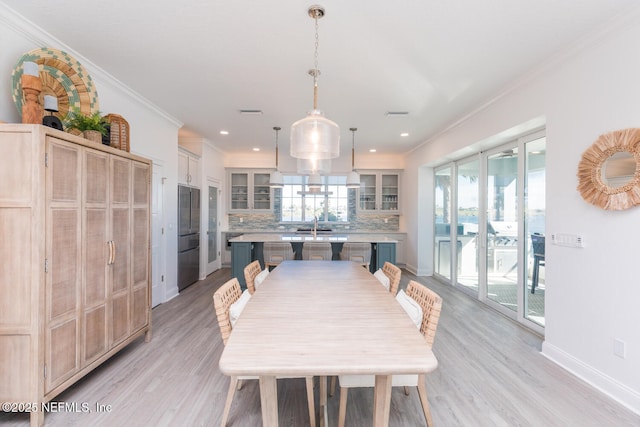 dining area with sink, ornamental molding, and light hardwood / wood-style floors