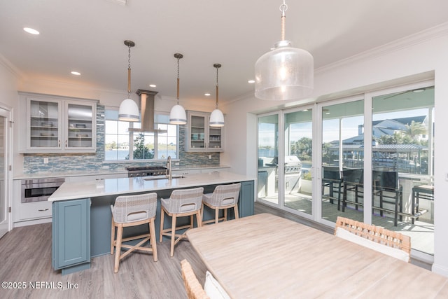 kitchen featuring a kitchen island with sink, decorative light fixtures, island range hood, and oven